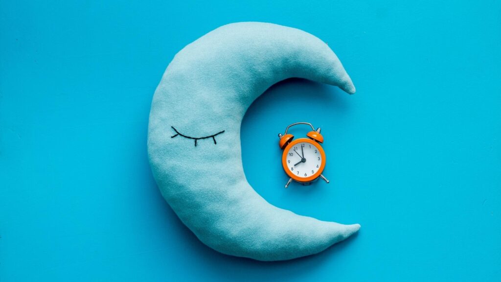 Moon pillow on a blue background showing a clock at 8pm. The ideal time for 10 month old babies to go to bed.