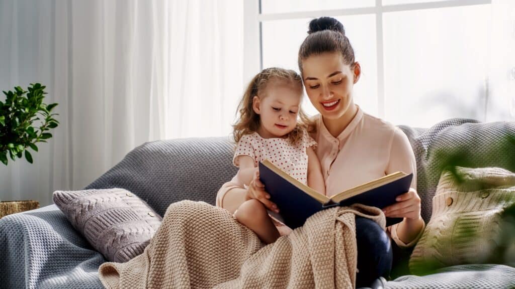 Reading A Book With A Toddler On a grey couch