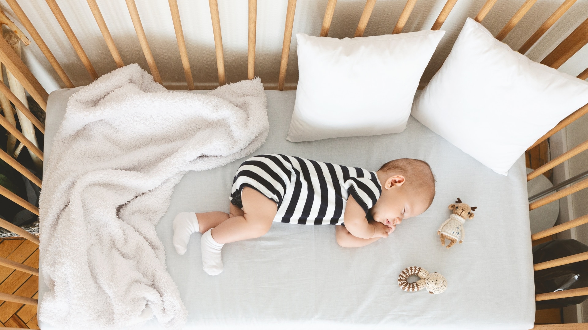 3 To 2 Nap Transition - Baby in striped pyjamas lying in his crib