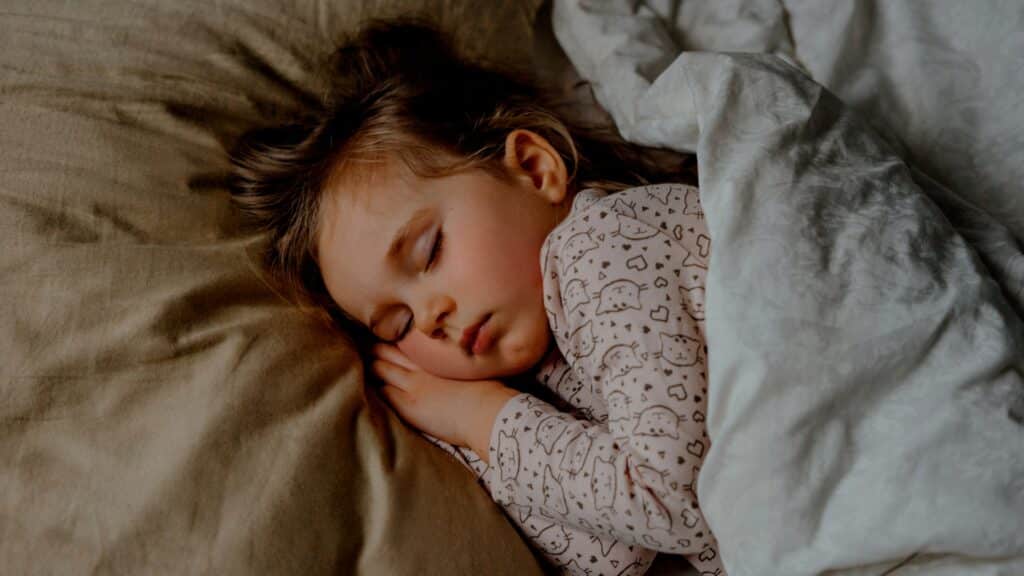 Toddler Sleeping deeply cozy in bed under duvet